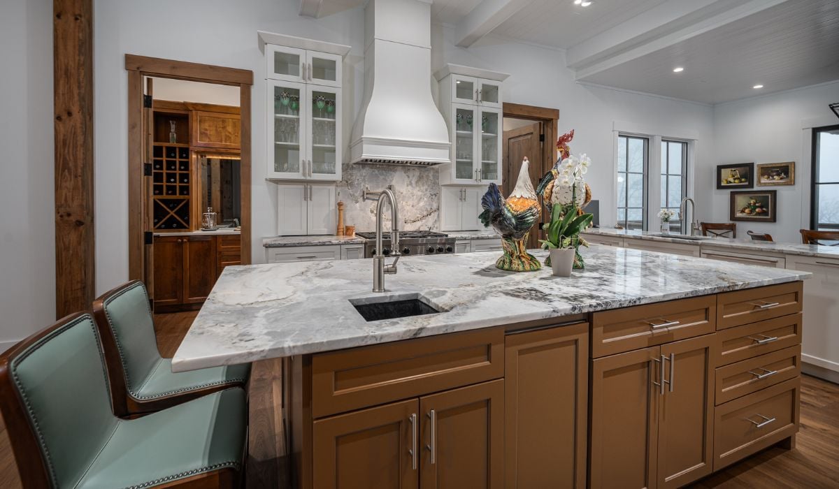 A traditional kitchen with brown island and white shaker cabinets.