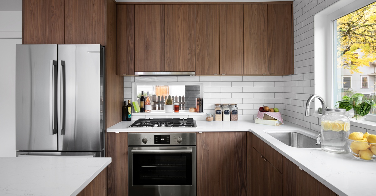 A modern kitchen featuring white countertops and a white backsplash, complemented by modern wood cabinets with minimal hardware.