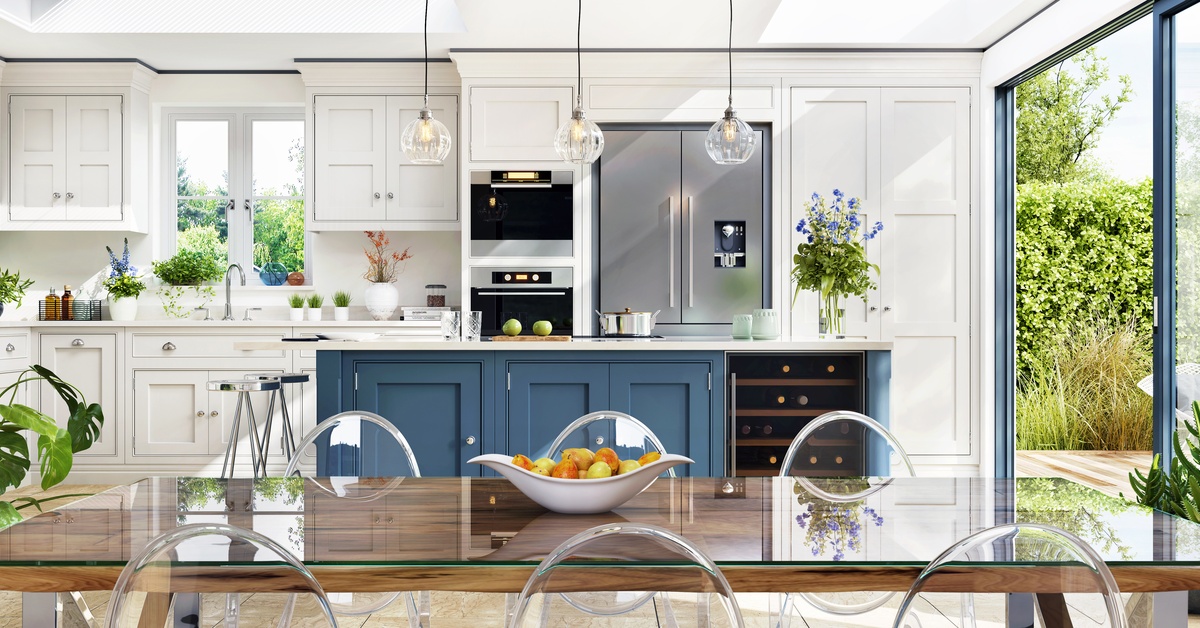 A spacious kitchen featuring classic white and blue two-tone cabinets paired with a contemporary seating area.