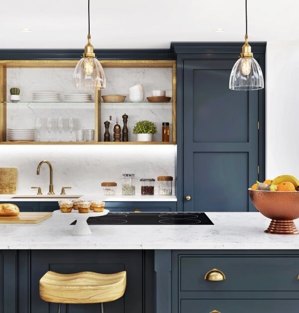 Bright kitchen with navy cabinets, marble island, pendant lights, open shelving, and a cozy seating area by large sunlit windows.