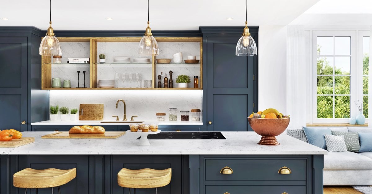 Bright kitchen with navy cabinets, marble island, pendant lights, open shelving, and a cozy seating area by large sunlit windows.